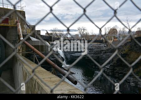 The waterfalls on the Hudson River at Coopers Cave in Glens Falls New York featuring old industrial elements along the waterfront. Stock Photo