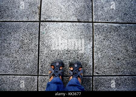 Top view of feet in blue color shoes standing on grey concrete floor
