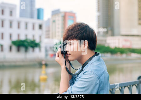 Young asian man tourist taking photos outdoor in the city Stock Photo