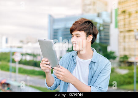 Young asian man tourist using digita; tablet outdoor in the city Stock Photo