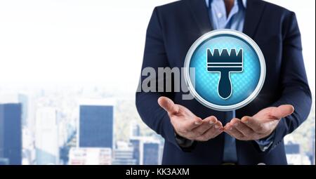 Digital composite of Clean brush icon and Businessman with hands palm open in city Stock Photo