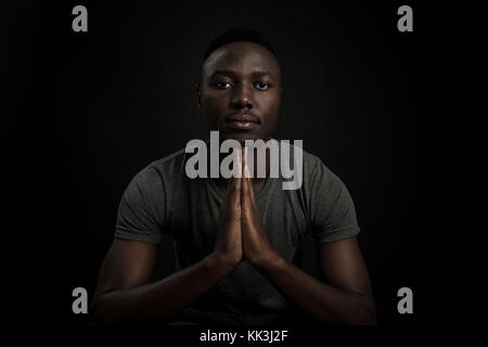 Headshot of serious confident young dark-skinned african male standing isolated against black studiobackground. Stock Photo