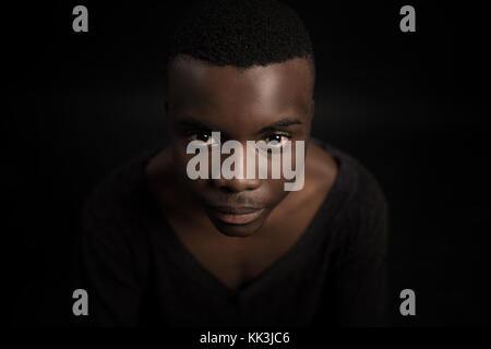 Headshot of serious confident young dark-skinned african male standing isolated against black studio background. Stock Photo