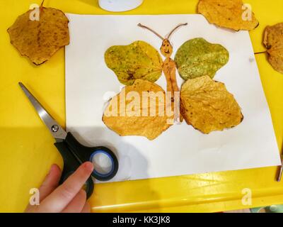 Children's hand-made from yellow autumn leaves in the form of a butterfly, children's creativity,