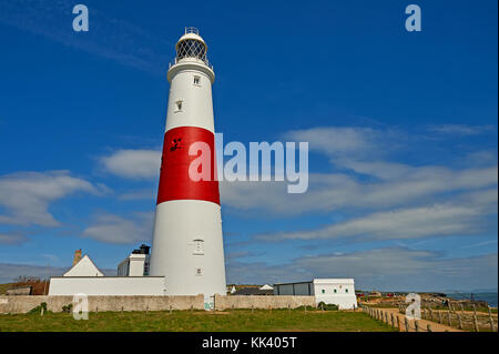 Portland Bill lighthouse in Dorset is a stereotypical white tower with wide red banding, seen against a blue sky. Stock Photo
