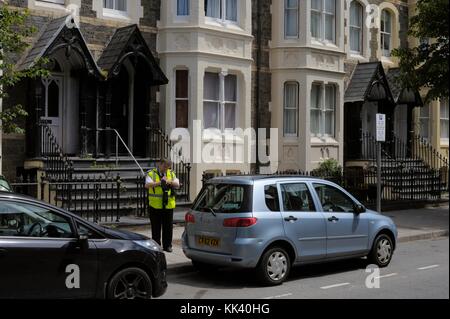 Traffic warden recording parking violation, Aberystwyth, Wales, UK Stock Photo