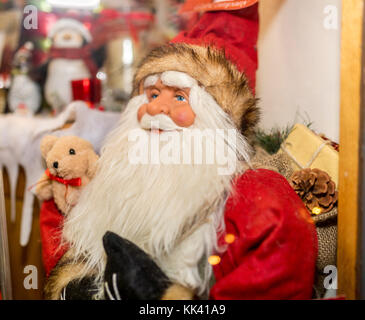 Traditional Santa Claus or Father Christmas dummy figure or mannequin on display with a teddy bear next to him in a toy shop window Stock Photo