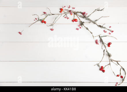 Christmas, New Year or Autumn background, flat lay composition of Christmas natural ornaments and fir branches, berries, rose hips and winter branches covered with moss, empty space for greeting text, congratulations, invitations Stock Photo