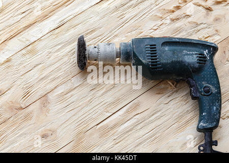 attachment on a drill, scrape, metal rotating brush. attachment is on a rough wooden surface Stock Photo
