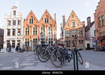 Bruges, Belgium - April 15, 2017: The bicycles on an old cobblestone street. Multicolored traditional Belgian houses in Bruges. Stock Photo
