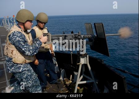 Sonar Technician Surface 1st Class Michael Miller fires a 50 cal machine gun as Gunner's Mate 2nd Class Michael Wakefield instructs during a training exercise aboard the guided-missile destroyer USS Jason Dunham DDG 109, Atlantic Ocean, 2012. Image courtesy Mass Communication Specialist 2nd Class William Jamieson/US Navy. Stock Photo