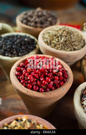 Variety of different spices with focus on pink Peruvian pepper, false pepper used in four peppers blends close up Stock Photo