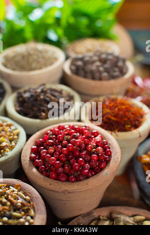 Variety of different spices with focus on pink Peruvian pepper, false pepper used in four peppers blends close up Stock Photo