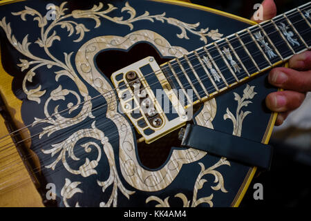 Close up on unidentifiable man using his fingers to hold up beautiful wooden stringed instrument with floral patterns Stock Photo