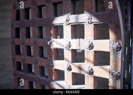 Angled view of a half shaded metal portcullis arched door with a flower pattern that is partially opened up at Death Valley National Park Stock Photo