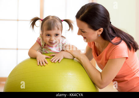 Mother with happy kid doing exercises with gymnastic ball at fitness class. Concept of caring for the baby's health. Stock Photo