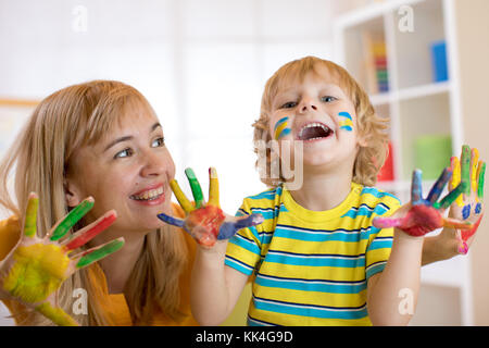 Smiling child boy and his mother having fun and showing hands painted in colorful paints Stock Photo