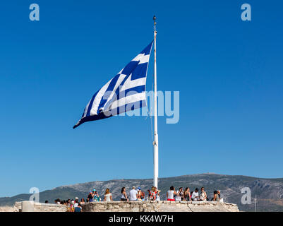 Tourists under a greek flag flying at the top of the Acropolis Athens, Greece Stock Photo