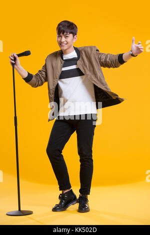 Cheerful young Chinese man singing with microphone Stock Photo