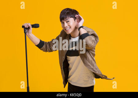 Cheerful young Chinese man singing with microphone Stock Photo