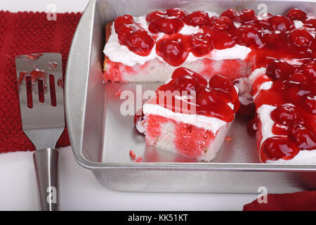 White cake topped with whipped topping and cherries in a baking pan Stock Photo