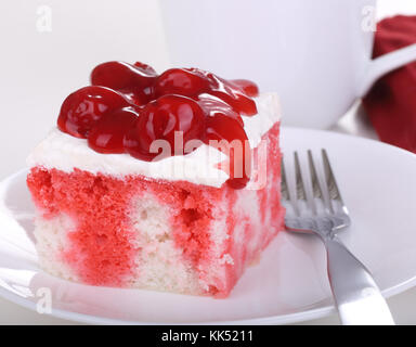 Piece of cake with whipped topping and cherries on a plate Stock Photo