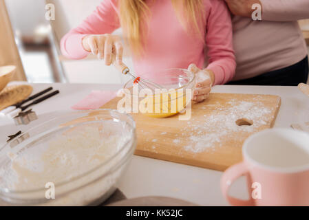 According to the recipe. Close up of a bowl with whipped eggs in it being used for cooking Stock Photo