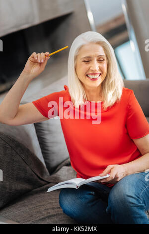 Sudden inspiration. Happy delighted positive woman holding her notebook and smiling while having a sudden inspiration Stock Photo