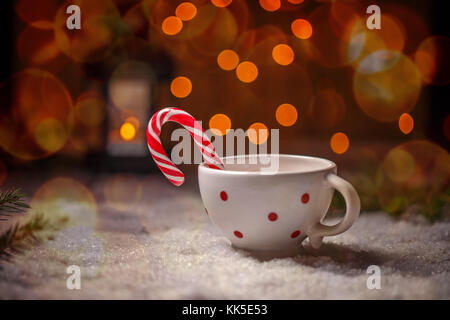 Dotted china cup with candy cane on Christmas style background Stock Photo