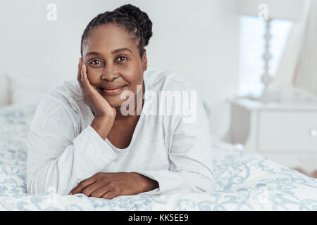 Smiling African woman lying on her bed in the morning Stock Photo