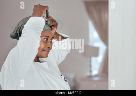 Stylish young African woman putting on a headscarf Stock Photo