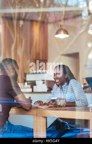 Young African couple talking while sitting together in a cafe Stock Photo