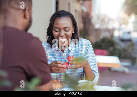 Smiling young African woman opening a gift from her boyfriend Stock Photo