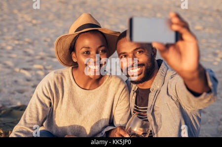 Happy young African couple taking selfies together at the beach Stock Photo