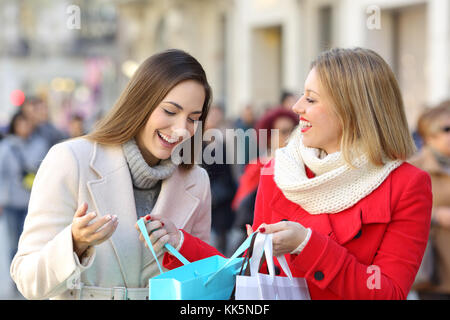 Two shoppers shooping and showing products outdoors on the street in winter Stock Photo