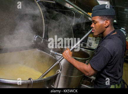 ATLANTIC OCEAN (Nov. 23, 2017) Lance Cpl. Wayne Meikle from Miami, assigned to the 26th Marine Expeditionary Unit, stirs a kettle of corn on the cob in the galley of the amphibious assault ship USS Iwo Jima (LHD 7) during Thanksgiving Day meal preparations. Iwo Jima, components of the Iwo Jima Amphibious Ready Group and the 26th Marine Expeditionary Unit are conducting a Combined Composite Training Unit Exercise that is the culmination of training for the Navy-Marine Corps team and will certify them for deployment. (U.S. Navy photo by Mass Communication Specialist 3rd Class Kevin Leitner/Relea Stock Photo