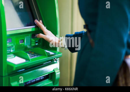 Photo of woman with clock on hand at green cash machine in room Stock Photo