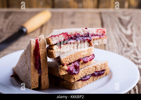 Peanut butter and jelly sandwich with whole wheat bread on rustic wooden table Stock Photo
