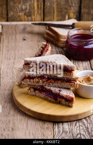 Peanut butter and jelly sandwich with whole wheat bread on rustic wooden table Stock Photo