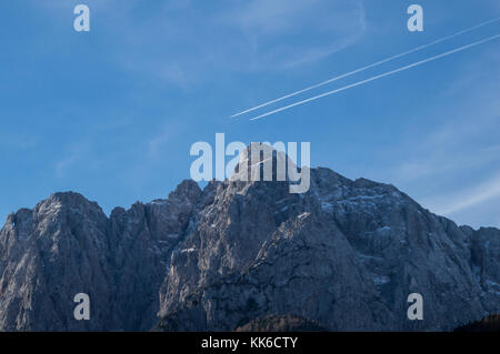 Two airplane contrails parallel to each other over the rugged peaks of the Julian Alps Stock Photo