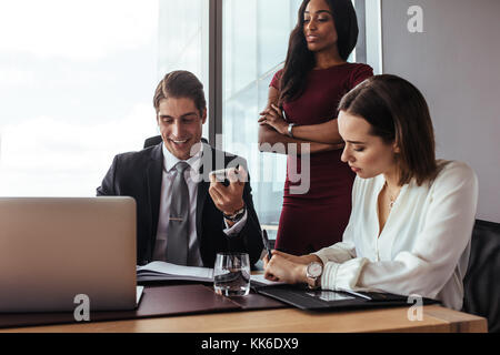 Successful businessman talking on mobile phone while working with his business team. business man speaking on the phone while working with colleagues Stock Photo
