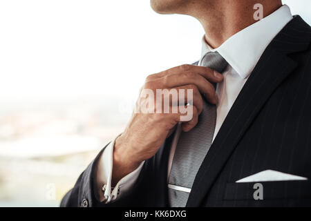 Close up of man in business suit correcting tie. Cropped shot of businessman adjusting his look. Stock Photo