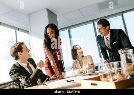 Group of diverse business people smiling during a meeting in office. Happy business colleagues laughing in a meeting in conference room. Stock Photo