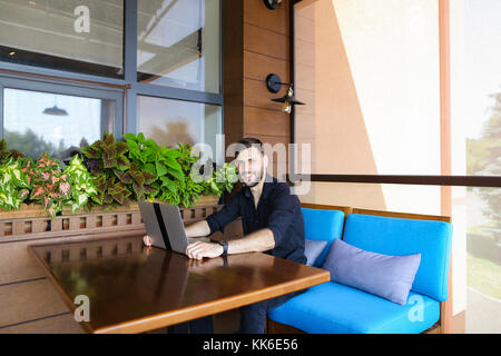 Happy businessman looking at camera working with laptop and talk Stock Photo