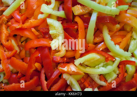 Natural background of sliced lengthwise stripes of ripe multi-colored peppers. Stock Photo