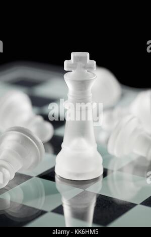 chess king with fallen chess pawn on board Stock Photo