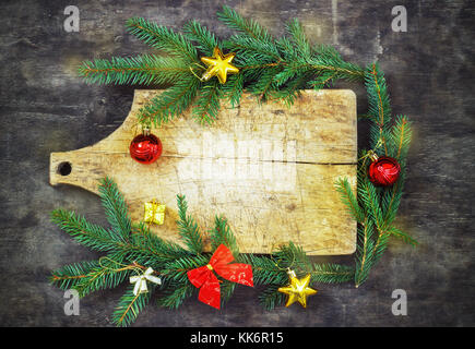 Old cutting board with spruce branches on a wooden background kitchen cooking christmas Stock Photo