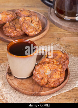 Glazed apple fritters and cup of coffee on a wooden plate Stock Photo