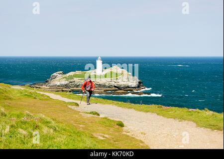 Walker on the South West Coast Path at Godrevy Head and lighthouse. North tip of St. Ives Bay, Cornwall, England, UK Stock Photo