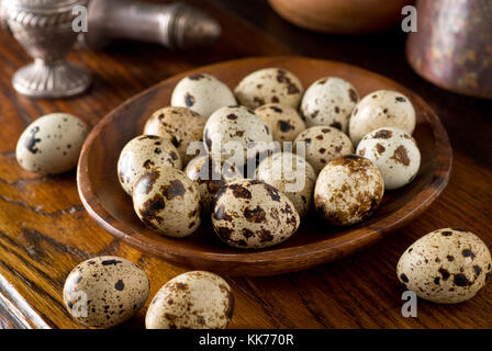 Quail eggs in a wooden bowl on a rustic table top setting. Stock Photo